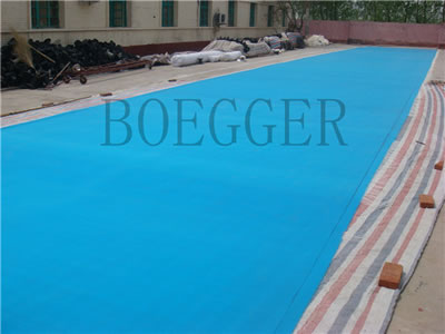 A large blue polyester filter belt is tiling on the ground.